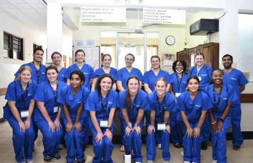 A group of people wearing blue scrubs poses for a photo indoors, possibly related to a medical internship.