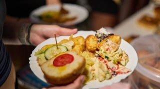 A plate filled with various foods, including a sandwich with tomato, salad, and fried items.