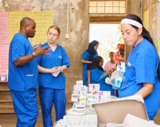 Medical personnel in blue scrubs organize supplies in a clinical setting.