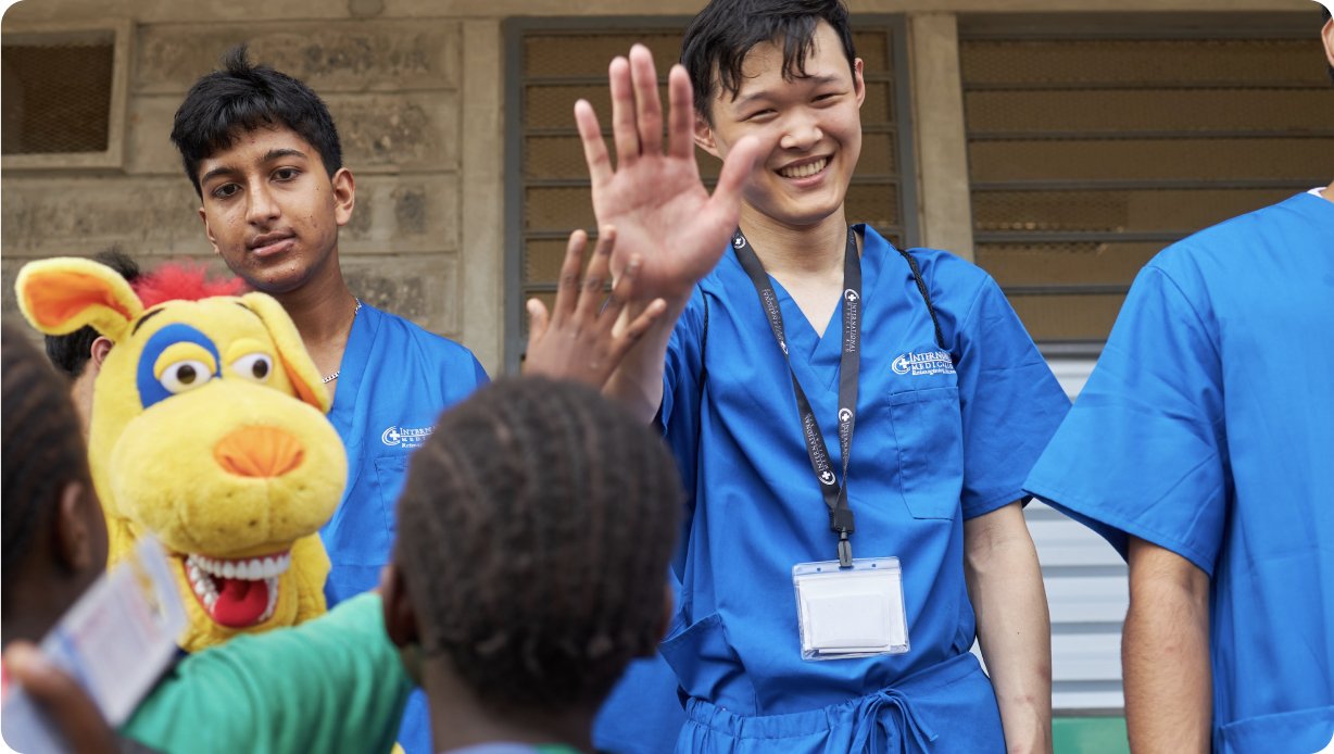 People in blue scrubs interacting with children, possibly in a medical setting.