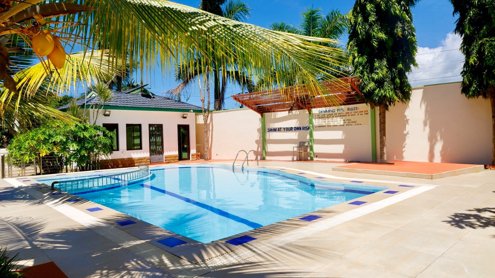 A pool with palm trees, a building, and a 