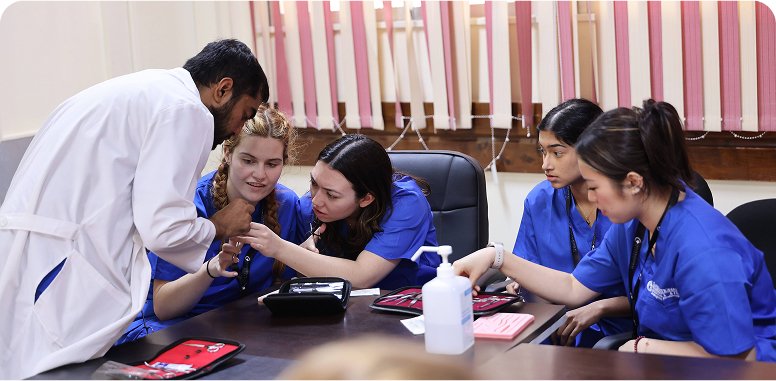 A group of young people in blue scrubs receiving medical training, possibly indicating high school healthcare internships.
