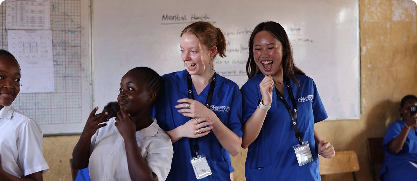 People in blue uniforms interacting and smiling, possibly during a high school healthcare internship.