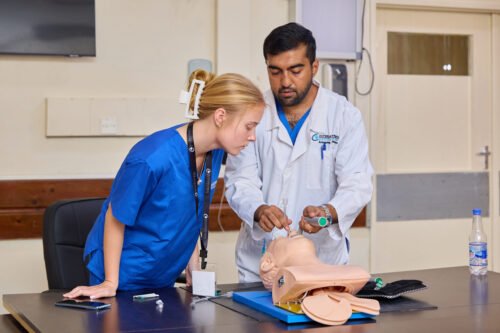 Two people practicing a medical procedure using a mannequin in a training setting.