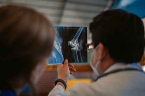 Two people examining a knee X-ray, likely in a medical setting.